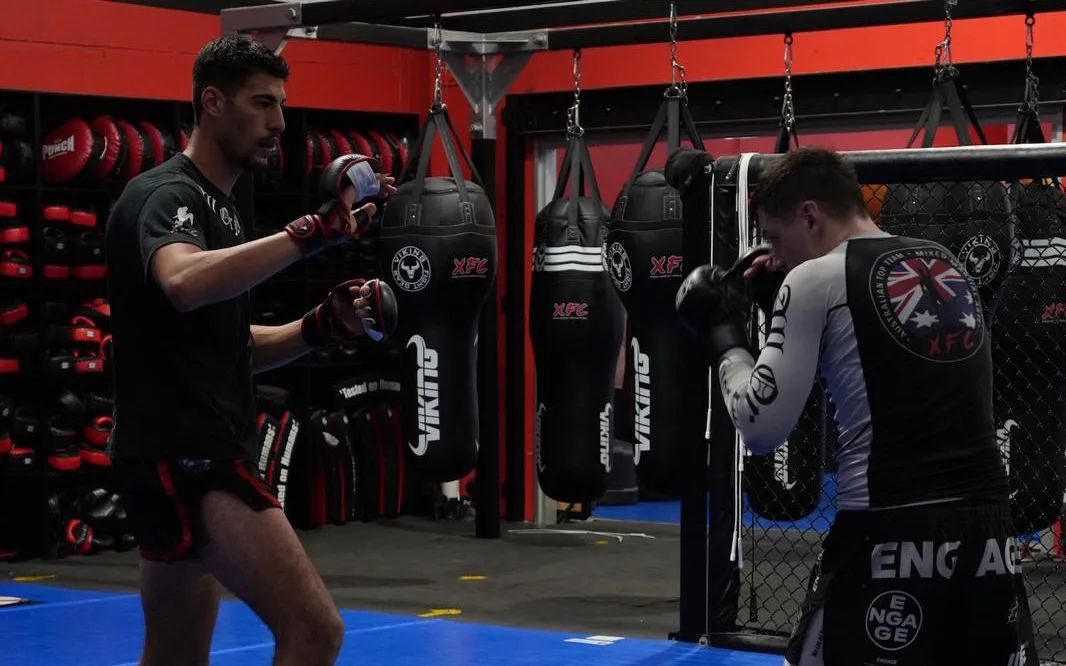 Two members squared up in gloves and shin guards for a sparring round