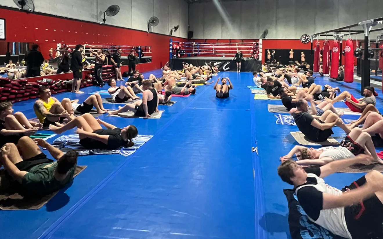 A packed class working through conditioning rounds on the main mat