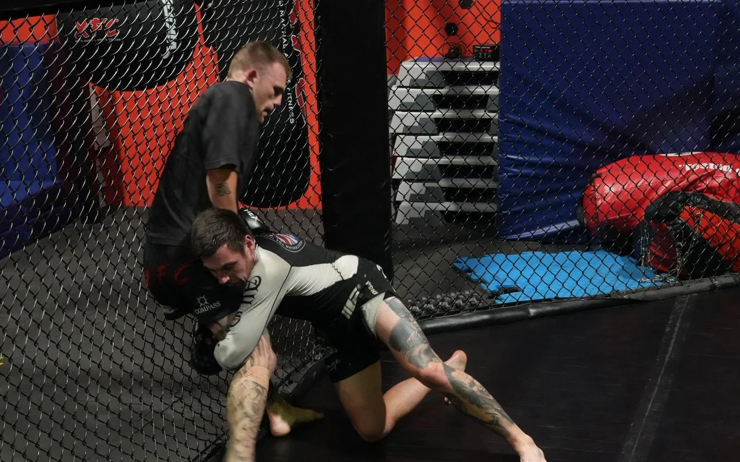 A takedown against the fence during an MMA round in the cage